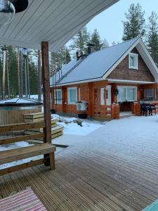 Cabaña de madera con porche y bancos en la nieve en Villa Kuuhimon Helmi, en Parkano