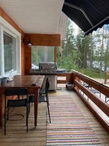 porche con mesa, sillas y parrilla en Villa Kuuhimon Helmi, en Parkano