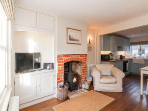 a living room with a fireplace and a chair at Shrimpers Cottage, Aldeburgh in Aldeburgh