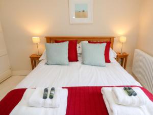 um quarto com uma cama branca e toalhas vermelhas e brancas em Shrimpers Cottage, Aldeburgh em Aldeburgh