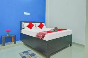 Bett mit roten Kissen in einem blauen Zimmer in der Unterkunft Flagship Hotel Tulsi Inn in Dānāpur