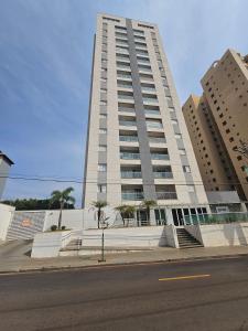 a tall white building with palm trees in front of it at Edíficio Sienna in Ribeirão Preto