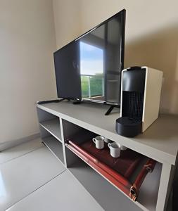 a desk with a tv and a computer on it at Edíficio Sienna in Ribeirão Preto