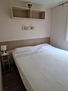 1 cama en un dormitorio con colcha blanca en Mobilhome 4/5 personnes, en Longeville-sur-Mer