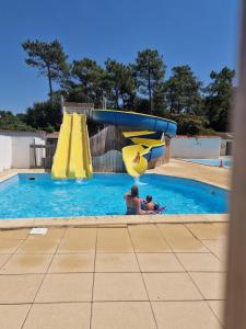 una mujer y un niño jugando en un tobogán de agua en una piscina en Mobilhome 4/5 personnes, en Longeville-sur-Mer