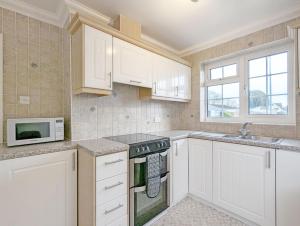 a kitchen with white cabinets and a microwave at Marine Lodge in Bognor Regis