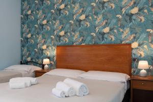 two beds in a room with a floral wallpaper at Hotel Riva Etrusca in Marina di Bibbona