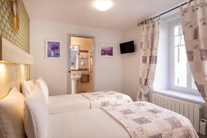 a hotel room with two beds and a window at Hôtel de Lion sur Mer in Lion-sur-Mer