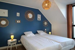 sypialnia z niebieską ścianą z łóżkiem i 2 lustrami w obiekcie Maison neuve proche de la plage 3 chambres / accès PMR / Parking w mieście Ploemeur