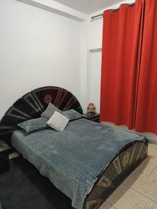 1 dormitorio con cama y cortina roja en Appartement une chambre, en Meknès