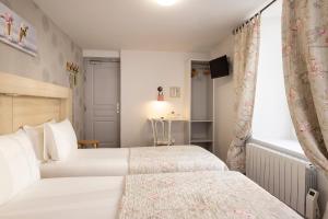 a bedroom with two beds and a window at Hôtel de Lion sur Mer in Lion-sur-Mer