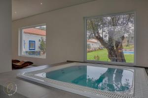 - une grande piscine dans une chambre dotée d'une grande fenêtre dans l'établissement Quinta do Chocalhinho Agroturismo & SPA, à Odemira