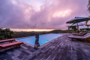 a swimming pool with two chairs and an umbrella at Pini Sentana Village in Nusa Penida