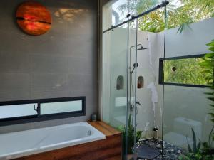 uma casa de banho com uma banheira e um chuveiro em vidro. em InnerZen Riverside homestay Ben Tre - Japanese style em Ấp Phú Hòa (3)