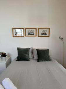 - une chambre avec un lit blanc et trois photos sur le mur dans l'établissement Apartamento no Centro de Lisboa, à Lisbonne