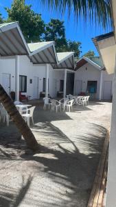 a group of white tables and chairs in front of a building at Sosun Villa Thoddoo in Thoddoo