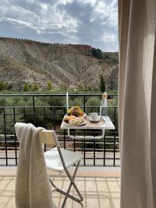 una mesa y una silla con un plato de comida en el balcón en La Rosita alojamiento rural, en Hinojares