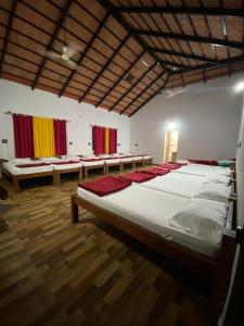 a large room with four beds and benches at Timber leaf stay in Avathi