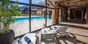 eine Terrasse mit weißen Stühlen und einem Pool in der Unterkunft Les alpages location appartement 108 in Lanslebourg-Mont-Cenis