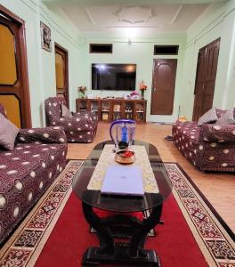 Ojas Home Bharatpur في بهاراتبور: غرفة معيشة مع مزهرية زجاجية على طاولة قهوة