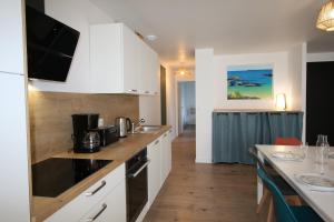 a kitchen with white cabinets and a counter top at Maison neuve proche de la plage 3 chambres / accès PMR / Parking in Ploemeur