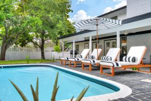 a pool with lounge chairs and an umbrella next to a house at Cactus Club - A Birdy Vacation Rental in San Antonio