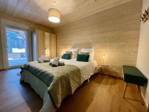 1 dormitorio con 1 cama grande y pared de madera en Chalet 2 marmottes Bain Nordique, en Gerbépal