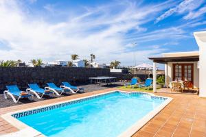 una piscina con sillas, una mesa y una valla en Villa Capricho en Playa Blanca