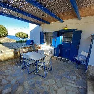 patio ze stołem i krzesłami oraz niebieskimi drzwiami w obiekcie Serenity Maisonnette w mieście Otziás