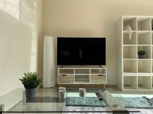 una sala de estar con TV en un centro de entretenimiento blanco en Coastal Elegance Maisonette en Limassol