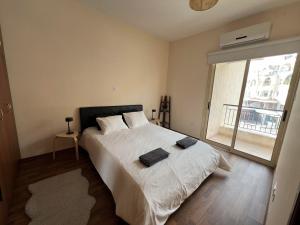 a bedroom with a bed with white sheets and a window at Coastal Elegance Maisonette in Limassol