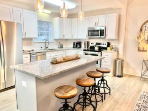 a kitchen with white cabinets and a counter with stools at King Suite- Walk to UNC/Franklin St, Near Hospital in Chapel Hill