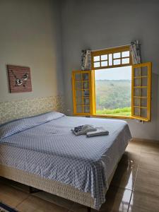 瓜拉雷马Sitio Aconchego Verde Guararema的一间带床和大窗户的卧室