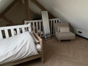 1 dormitorio con cama, silla y espejo en De Slaapsoof en Lier