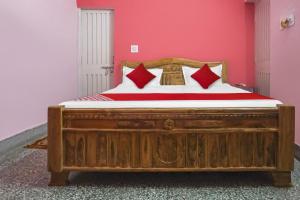 a bedroom with a wooden bed with red pillows at OYO Flagship Hotel Kashyap Heritage in Patna