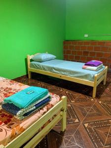 2 camas en una habitación con una pared verde en hospedaje don mario en San Ignacio