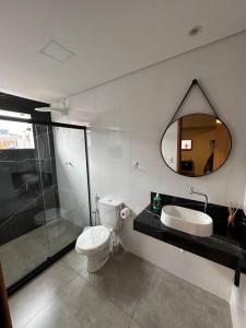 a bathroom with a toilet and a sink and a mirror at Apartamento/Loft 06 em Cabo Frio in Cabo Frio