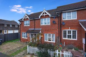 a red brick house with a white fence at Comfortable stylish Townhouse in Ashford sleeps 5 Netflix 2 Parking spaces Perfect for Contractors and Families in Ashford