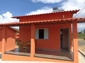 a small red house with a table and chairs at Chalés Cantin da Serra - Serra da Canastra/MG in São Roque de Minas