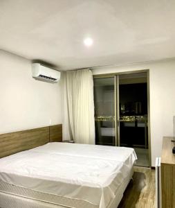 1 dormitorio con cama blanca y ventana en Suíte Master - com vista panorâmica!!!, en Río de Janeiro