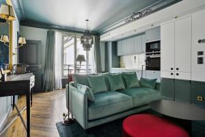 a living room with a green couch and a kitchen at Séjours Parisiens - Suites Haussmann, Malesherbes & Madeleine in Paris