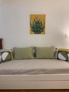 um sofá contra uma parede branca com um quadro de cactos em Completo Monoambiente de Montevideo Bliss em Montevidéu
