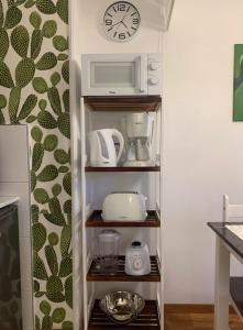 eine Küche mit einem Regal mit einer Mikrowelle und Geräten in der Unterkunft Completo Monoambiente de Montevideo Bliss in Montevideo