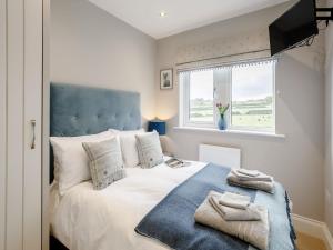 a bedroom with a bed with a blue headboard and a window at 2 Bed in Holmfirth 82193 in Meltham