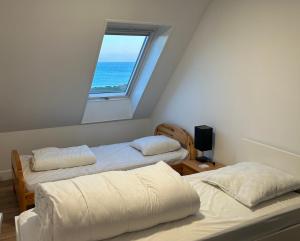 two beds in a room with a window at Maison d'exception face à l'océan in Lampaul-Plouarzel