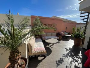 un patio avec un canapé, une table et un palmier dans l'établissement Riad Safina, à Marrakech