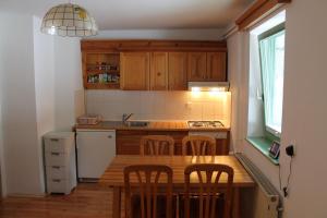 a kitchen with wooden cabinets and a wooden table with chairs at Apartma Jurček Rogla in Rakovec