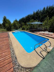 a swimming pool with a chair and an umbrella at Cabaña Ojo del Volcán in Pucón