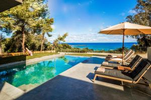 a swimming pool with two lounge chairs and an umbrella at Luxury Villa Mon I Vassilikos in Vasilikos