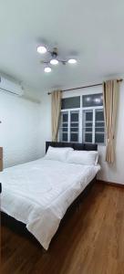 a large white bed in a bedroom with two windows at Pharungruang House Thatphanom Nakonphanom พารุ่งเรืองเฮ้าส์ in That Phanom